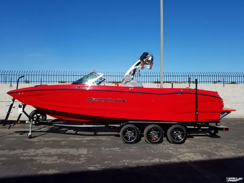 Slide: The Image of Red 2021 MasterCraft X26 boat on trailer, parked outdoors. - 7
