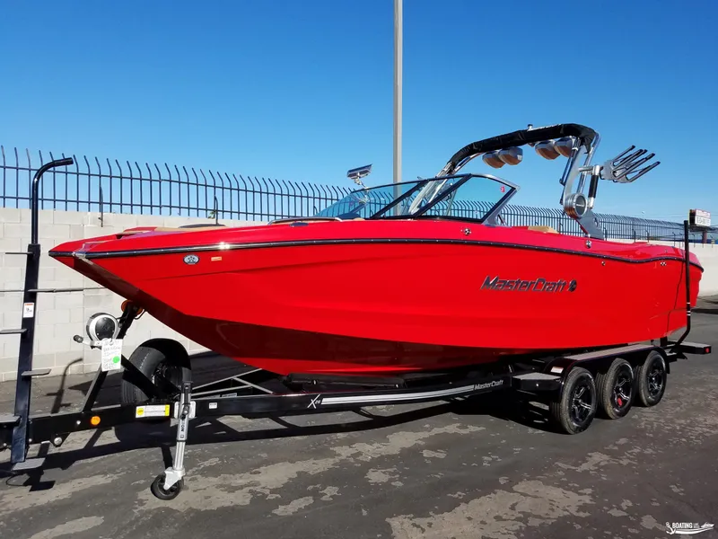 Slide: The Image of 2021 MasterCraft X26 boat in vibrant red on a trailer, parked outdoors. - 8