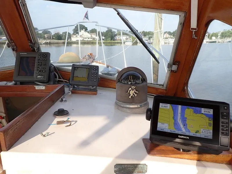 Slide: The Image of 1983 Dyer 29 Downeast Express boat cockpit with navigation equipment and scenic water view. - 14