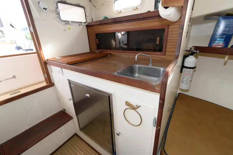 Slide: The Image of 1983 Dyer 29 Downeast Express boat interior with compact kitchen and sink. - 17
