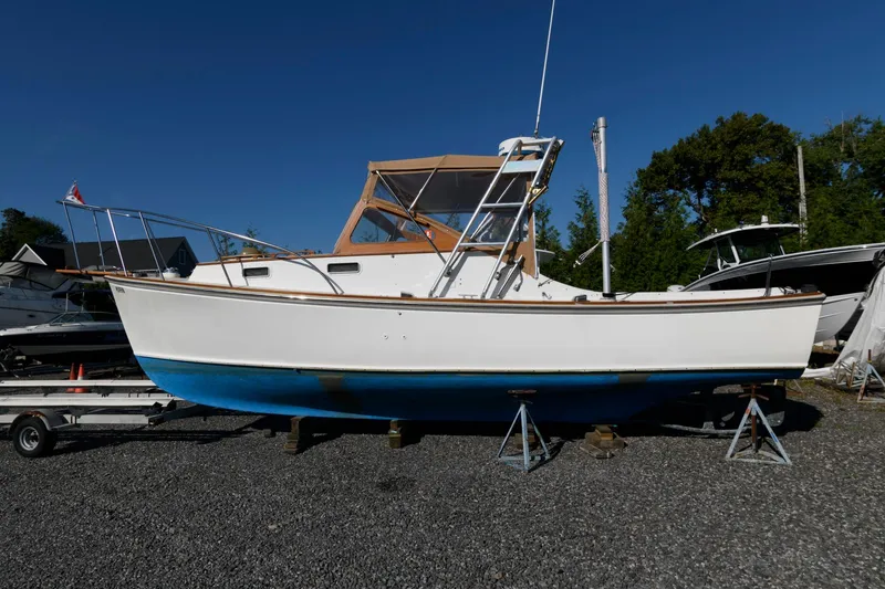 Slide: The Image of 1983 Dyer 29 Downeast Express boat on stands, white hull, blue bottom, outdoor setting. - 4