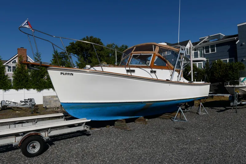 Slide: The Image of 1983 Dyer 29 Downeast Express boat on land, white hull, blue bottom, named "Puffin." - 5
