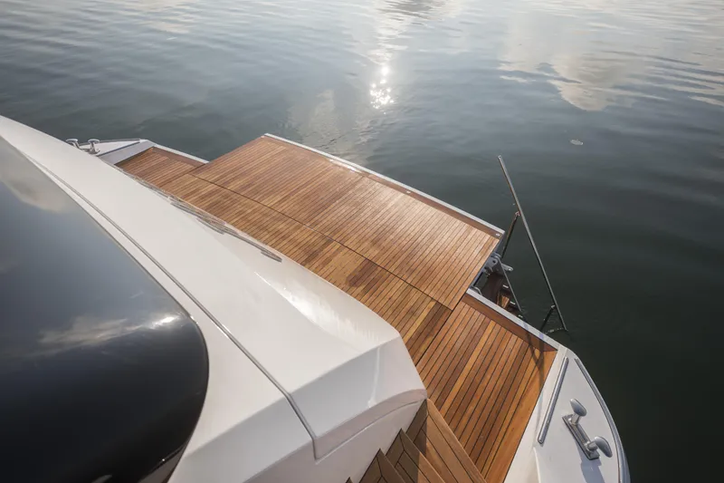 Slide: The Image of 2023 Mangusta Gransport yacht with sleek wooden deck on calm water. - 14