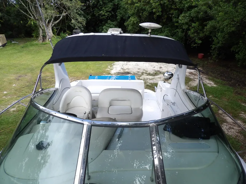 Slide: The Image of 2005 Sea Ray 360 Sundancer boat with black canopy and white seating, parked on grass. - 24