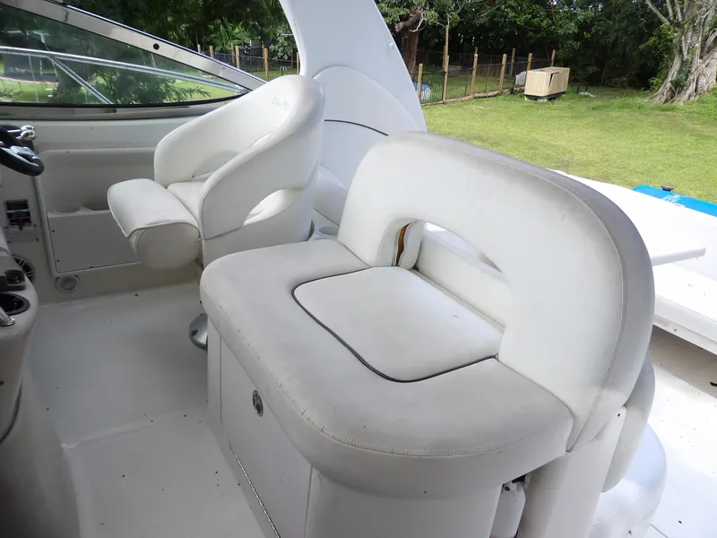 Slide: The Image of 2005 Sea Ray 360 Sundancer cockpit with white seating and helm, surrounded by greenery. - 31