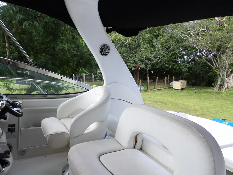 Slide: The Image of 2005 Sea Ray 360 Sundancer cockpit with white seating and lush greenery background. - 32
