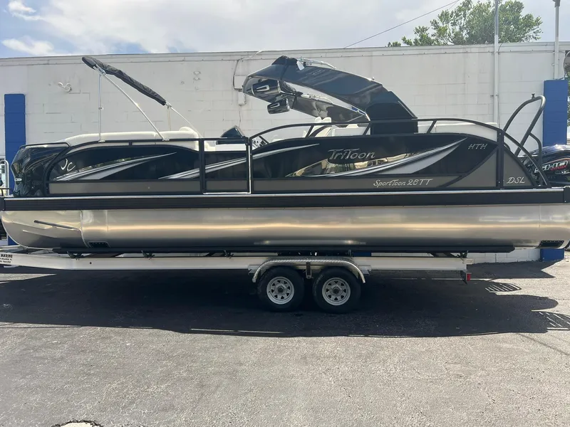 Slide: The Image of 2025 JC 26 SportToon TT DSL pontoon boat on trailer, sleek black design. - 0