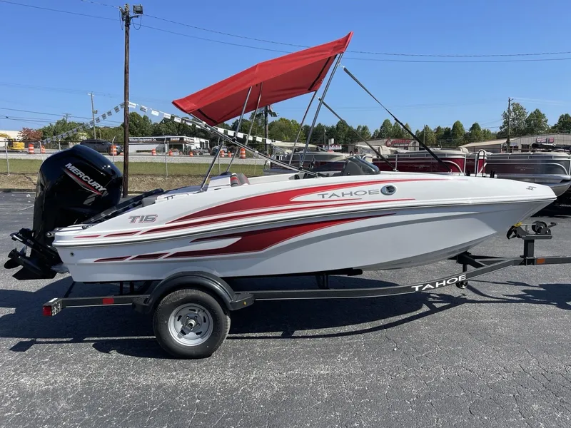 Slide: The Image of 2024 Tahoe T16 boat with red canopy on trailer, parked outdoors. - 2