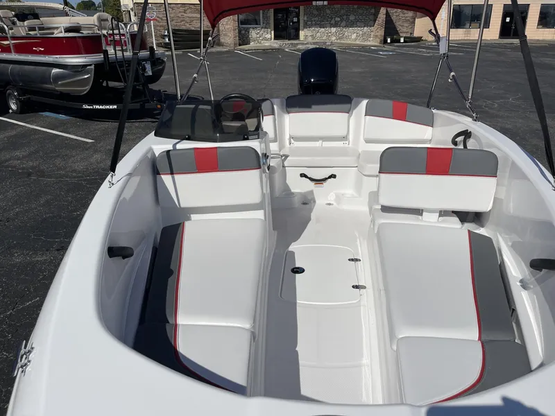 Slide: The Image of 2024 Tahoe T16 boat interior with red and gray seating, parked outdoors. - 7