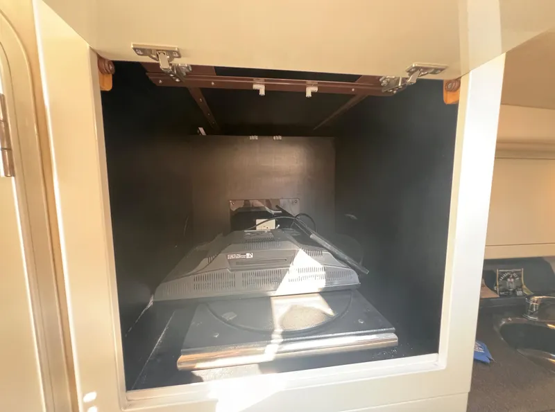 Slide: The Image of Storage compartment inside 2000 Wellcraft 45 Excalibur boat, featuring a mounted TV. - 25
