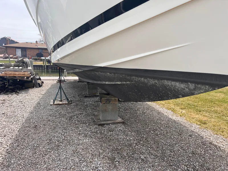 Slide: The Image of 2000 Wellcraft 45 Excalibur boat on stands, side view, gravel ground. - 49