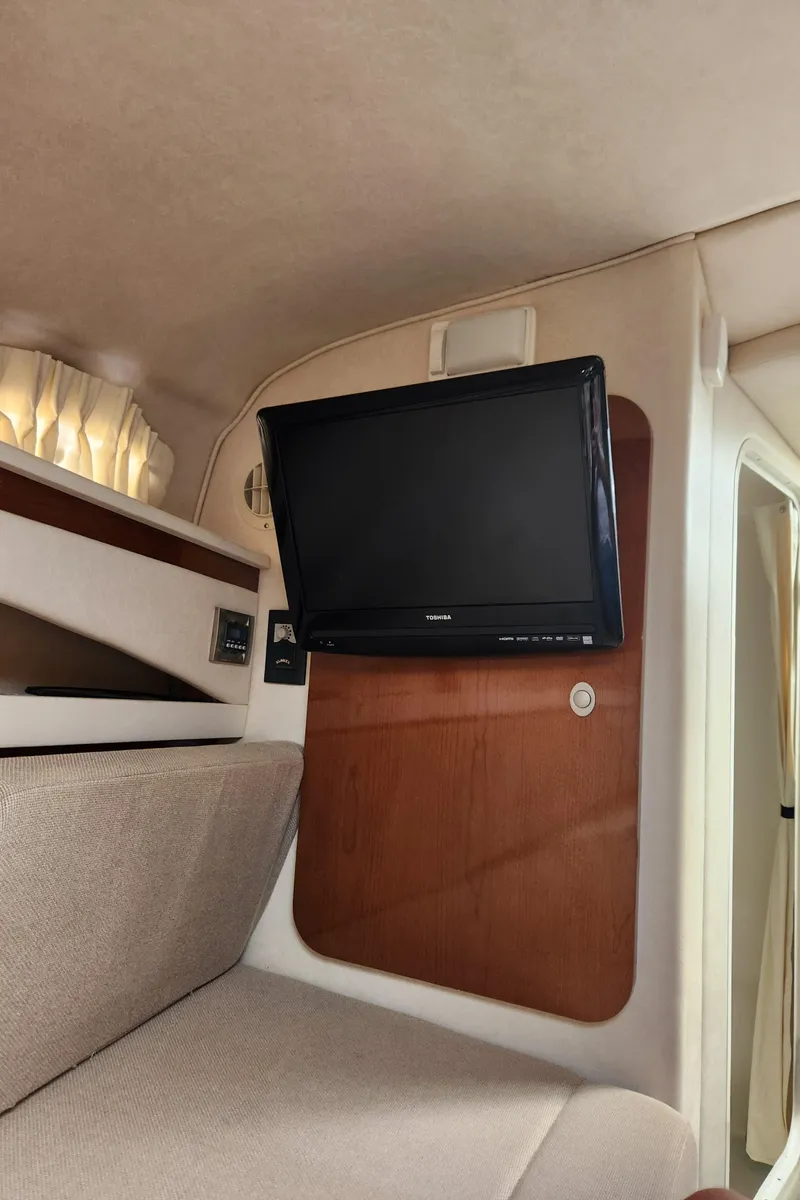 Slide: The Image of 2008 Sea Ray 260 Sundancer cabin interior with mounted TV and cozy seating. - 12