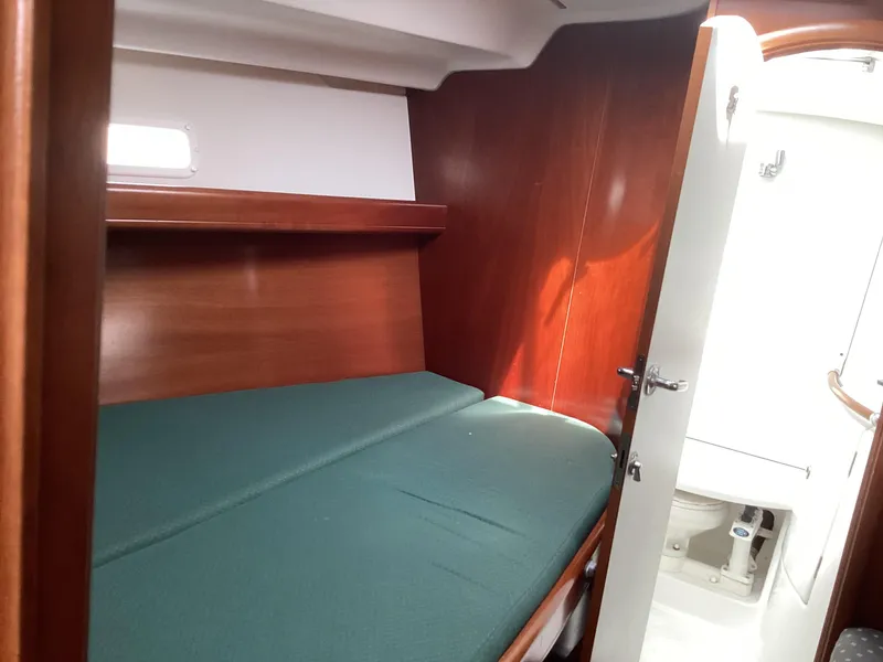 Slide: The Image of Beneteau 393 2002 cabin interior with green bedding and wooden finish. - 15