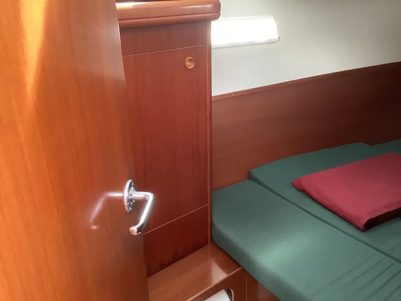 Slide: The Image of Interior cabin of 2002 Beneteau 393 sailboat with wooden finish and green bedding. - 16