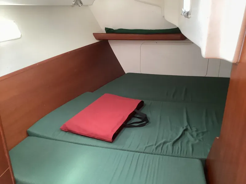 Slide: The Image of Cozy cabin interior of 2002 Beneteau 393 sailboat with green bedding and red cushion. - 21