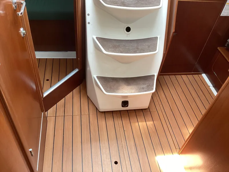 Slide: The Image of Interior of 2002 Beneteau 393 sailboat with wooden flooring and white steps. - 25