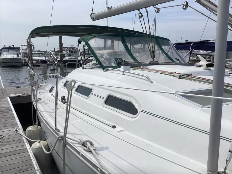 Slide: The Image of 2002 Beneteau 393 sailboat docked at marina, featuring sleek white design and green canopy. - 33