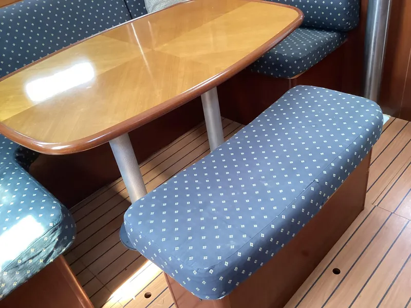 Slide: The Image of Beneteau 393 2002 interior with wooden table and blue upholstered seating. - 4