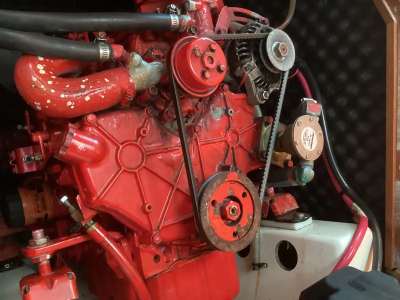 Slide: The Image of Red engine of a 2002 Beneteau 393 sailboat, featuring belts and hoses. - 41