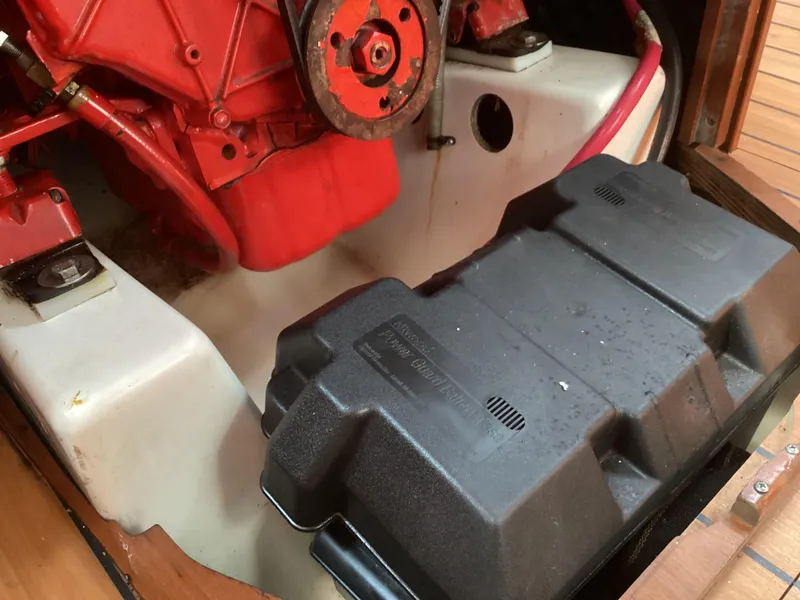 Slide: The Image of Engine compartment of 2002 Beneteau 393 sailboat, featuring red engine and black battery box. - 42