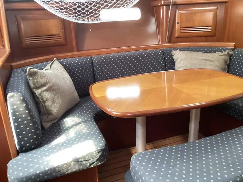 Slide: The Image of Cozy dining area in 2002 Beneteau 393 sailboat with cushioned seating and wooden table. - 5