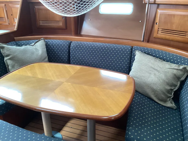 Slide: The Image of Cozy interior of 2002 Beneteau 393 sailboat with wooden table and cushioned seating. - 9