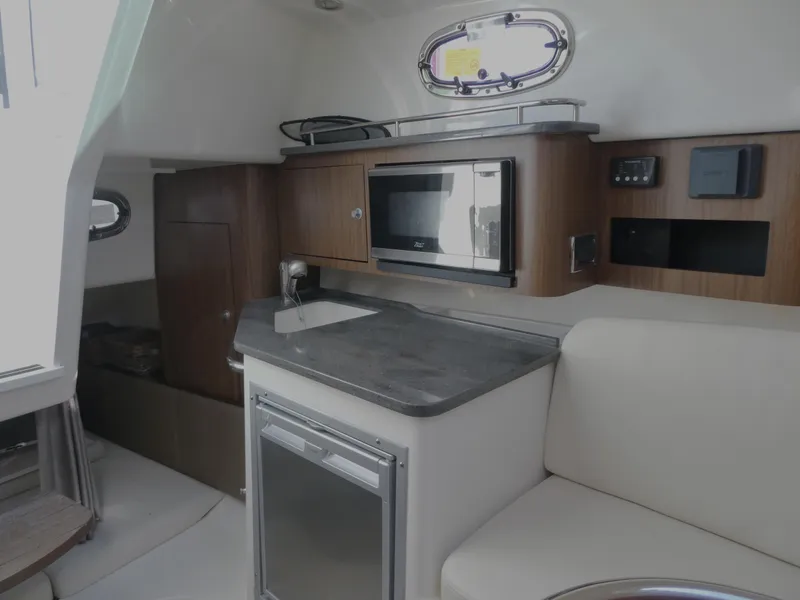 Slide: The Image of 2024 Boston Whaler 285 Conquest cabin interior with kitchenette and seating area. - 13