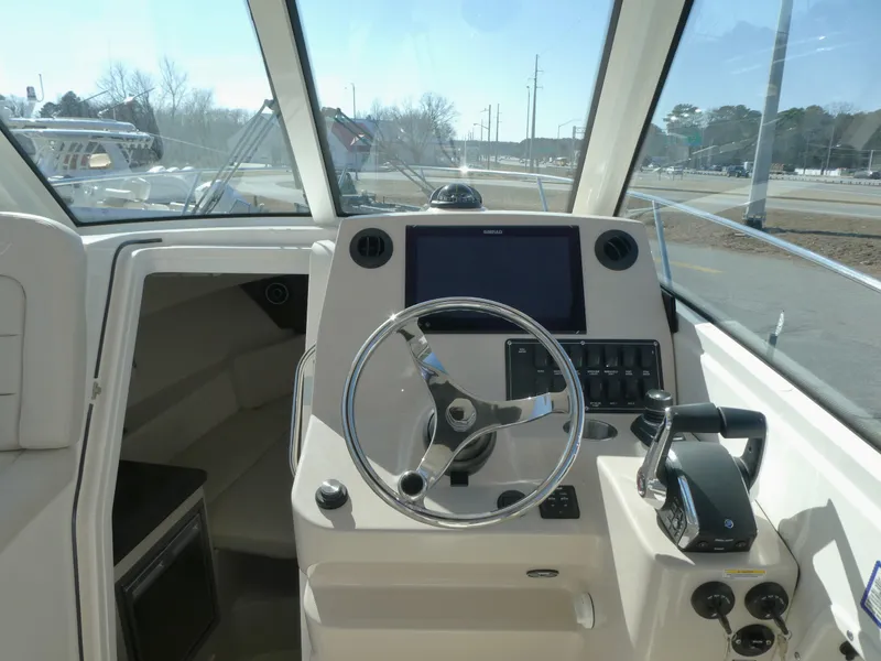 Slide: The Image of 2024 Boston Whaler 285 Conquest helm with steering wheel and navigation controls. - 7