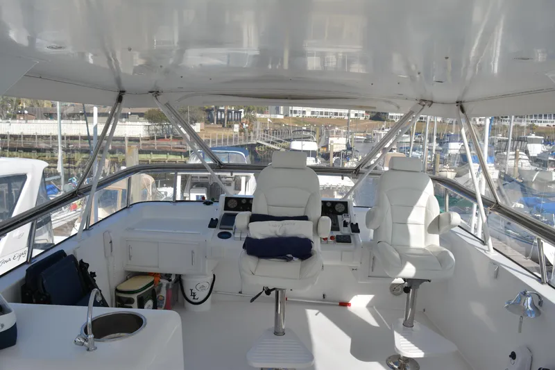 Slide: The Image of 1989 Viking Motor Yacht helm with white seating and marina view. - 20