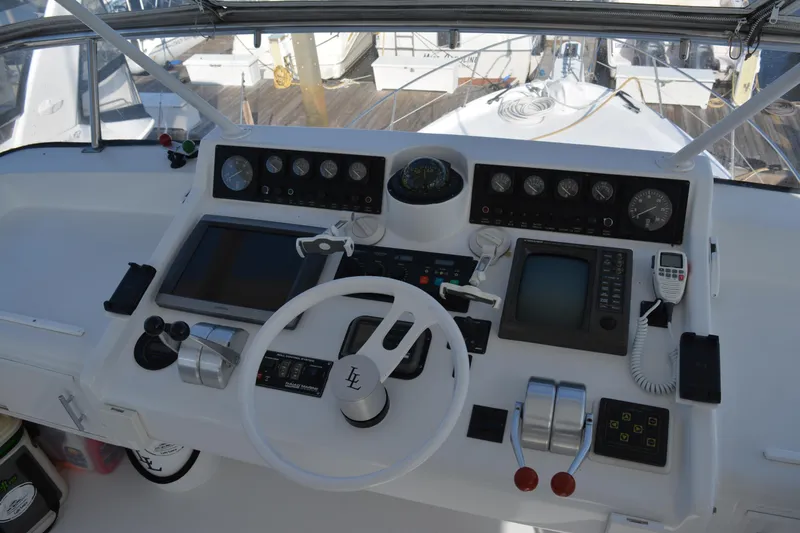 Slide: The Image of 1989 Viking Motor Yacht helm with steering wheel, navigation controls, and gauges. - 23