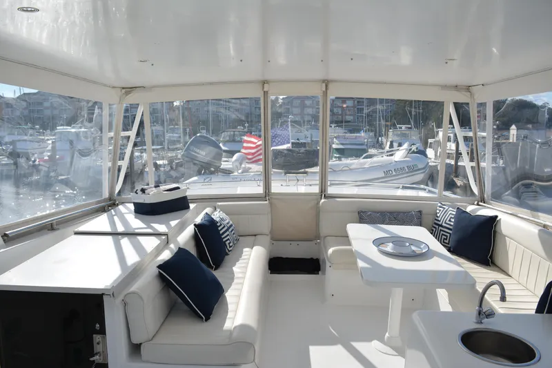 Slide: The Image of 1989 Viking Motor Yacht interior with white seating, blue cushions, and marina view. - 26