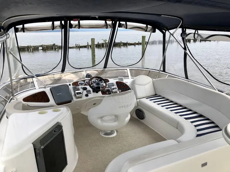 Slide: The Image of 2005 Meridian 459 Motoryacht cockpit with seating, steering wheel, and water view. - 7