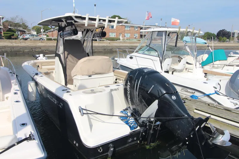 Slide: The Image of 2017 Sailfish 236 CC boat docked, featuring a powerful outboard motor and spacious deck. - 1