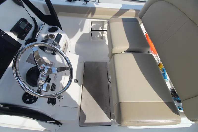 Slide: The Image of 2017 Sailfish 236 CC boat interior with steering wheel and beige seating. - 16
