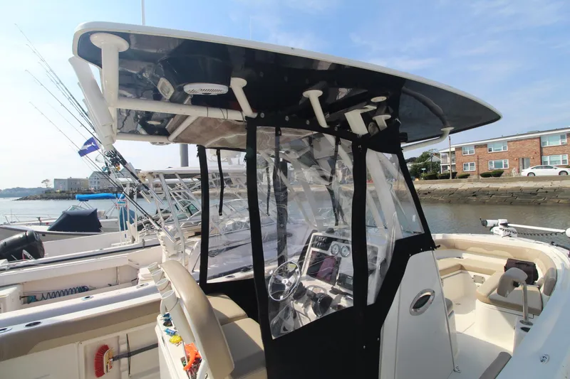 Slide: The Image of 2017 Sailfish 236 CC boat with T-top and console, docked near waterfront buildings. - 27