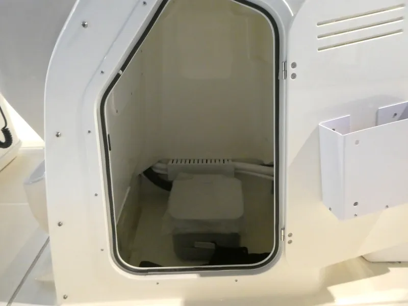 Slide: The Image of 2024 Boston Whaler 210 Montauk storage compartment with open door, showcasing interior space. - 12