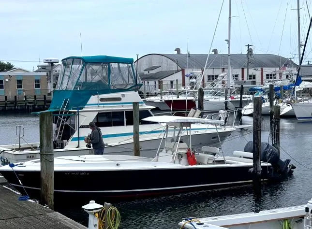 The Image of 1990 Intrepid 30 Console Cuddy boat docked in a marina with other vessels. - 1