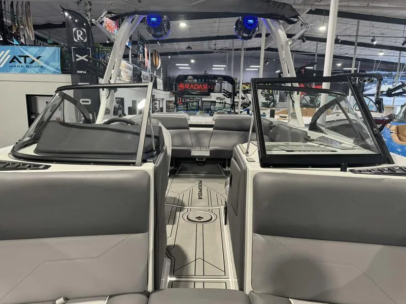 Slide: The Image of 2025 Moomba Max boat interior with gray seating and open windshield in showroom. - 11