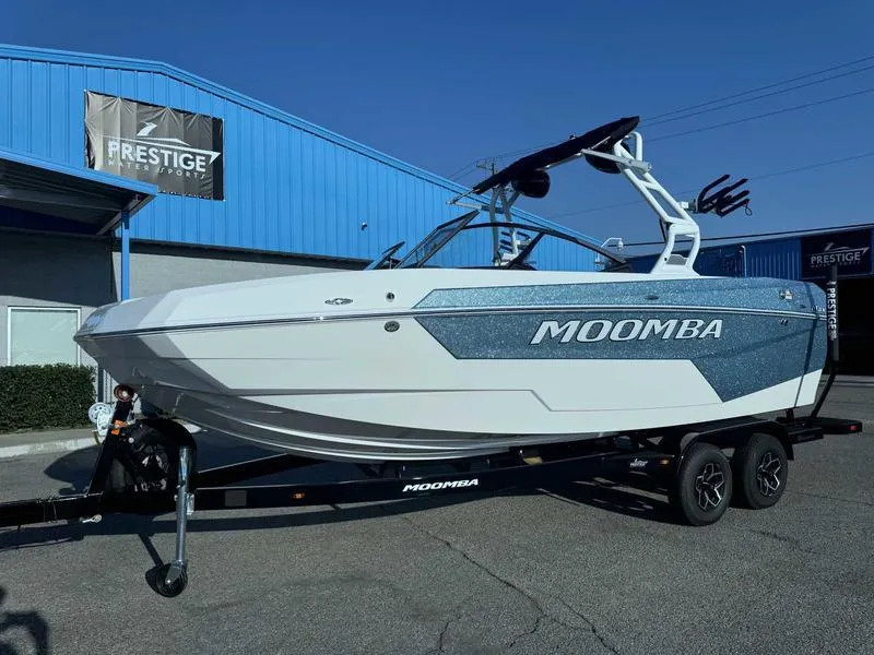 Slide: The Image of 2025 Moomba Max boat on trailer at Prestige dealership, blue and white design. - 14