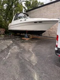 Slide: The Image of 2000 Sea Ray 340 Sundancer boat on stands, parked outdoors near a building. - 12