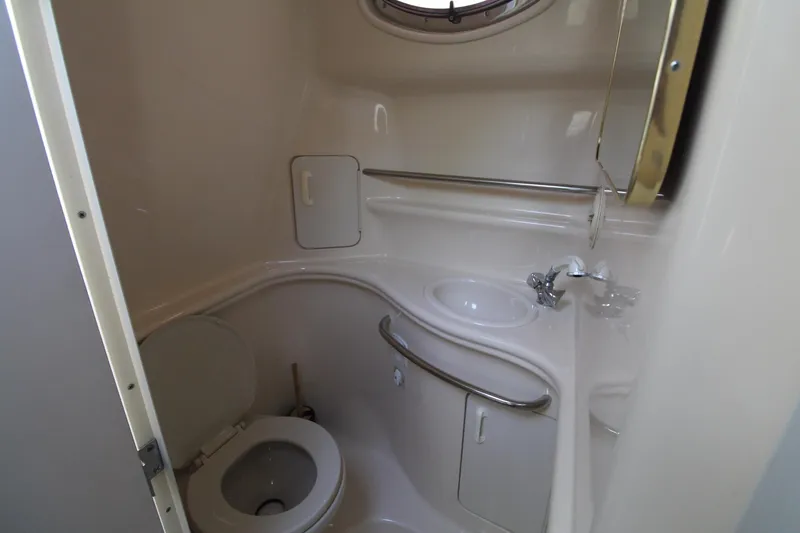Slide: The Image of Compact bathroom in 2000 Sea Ray 340 Sundancer yacht, featuring toilet, sink, and porthole. - 40