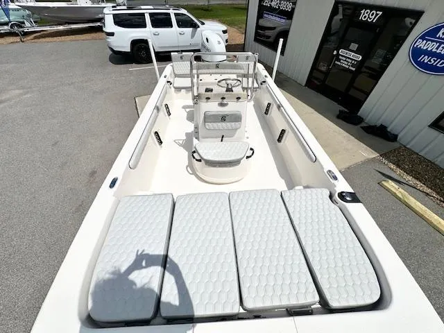 Slide: The Image of 2025 Carolina Skiff 19 LS boat with spacious deck and seating, parked outside a building. - 12