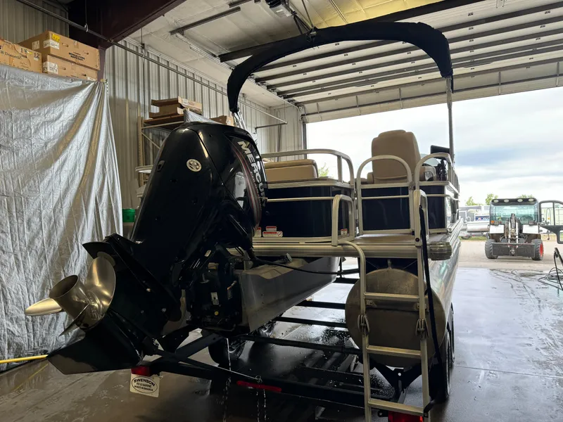 Slide: The Image of 2019 Sun Tracker Fishin' Barge 20 DLX in a garage, rear view with motor. - 3