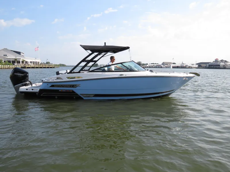 Slide: The Image of 2025 Monterey 255 Super Sport boat on calm water, with a scenic coastal backdrop. - 5