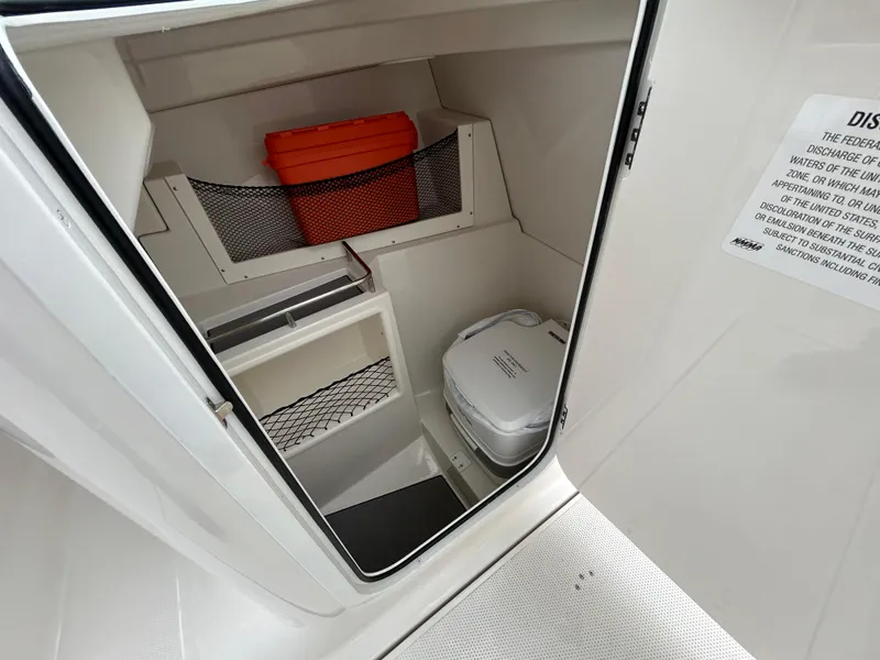 Slide: The Image of 2024 Sailfish 226 DC boat interior storage with portable toilet and safety equipment. - 14