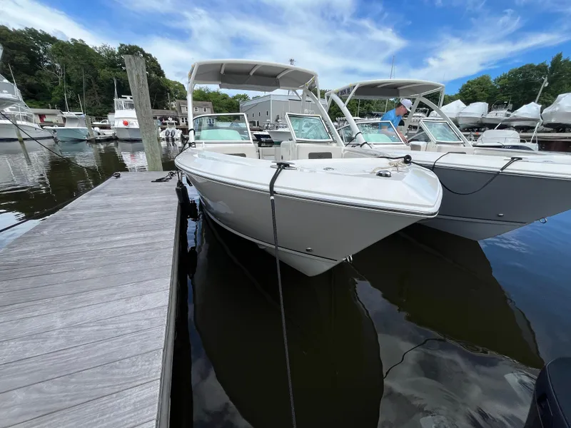 Slide: The Image of 2024 Sailfish 226 DC boat docked at marina under blue sky. - 2