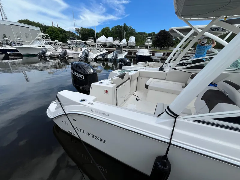 Slide: The Image of 2024 Sailfish 226 DC boat docked in a marina with Suzuki outboard motor. - 4
