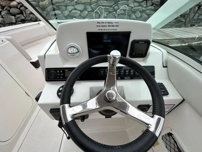 Slide: The Image of 2024 Sailfish 226 DC boat dashboard with steering wheel and navigation controls. - 9