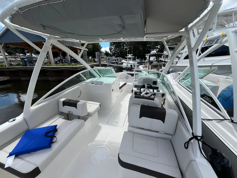 Slide: The Image of 2024 Sailfish 226 DC boat interior with seating and helm, docked at marina. - 16