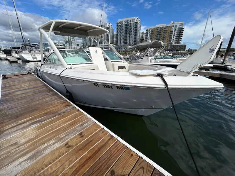 Slide: The Image of 2024 Sailfish 226 DC boat docked at marina with city skyline. - 2